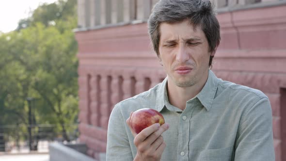 Young Adult Male Shopper Customer Wants to Eat Delicious Juicy Ripe Apple Sniffs Makes Grimace of alt