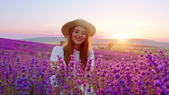 Beautiful Young Woman Wearing White Dress and Hat Standing in a Lavender Field