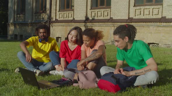 Divese Students Streaming Video on Laptop Outdoors alt