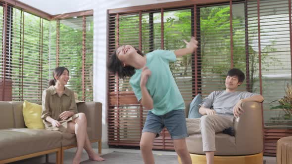 Happiness cheerful asian family dad mom and son funny dancing in living room