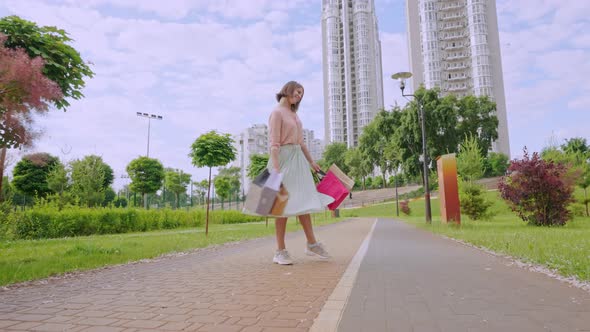 Joyful Woman Walks with Varicoloured Paper Bags