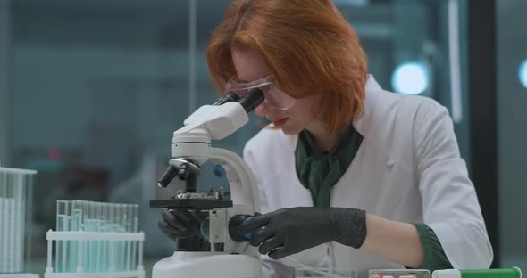 Woman Professional Microbiologist Is Researching Analysis in Laboratory, Looking in Microscope alt