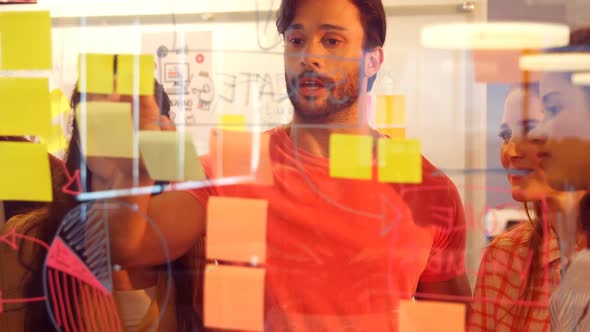 Business colleagues discussing over sticky notes alt