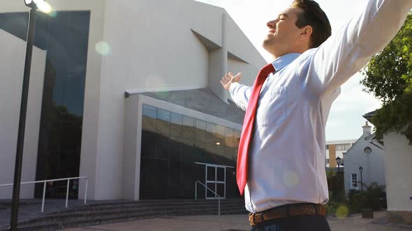 Businessman standing with arms outstretched alt