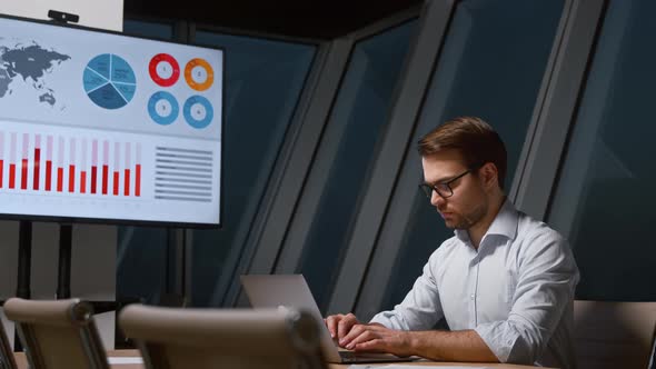 Young businessman in shirt typing letters on laptop alt