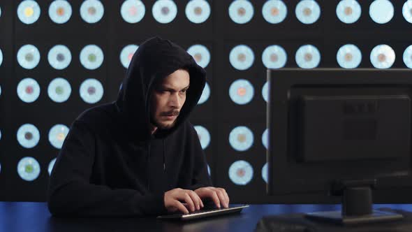 Bearded Mature Guy Computer Hacker Wearing Black Hoodie Works in Dark Room