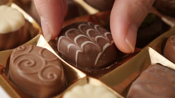 Box of chocolates choosing one with hand slow tilt 4K 2160p 30fps UltraHD footage - Hand pick  gift  alt