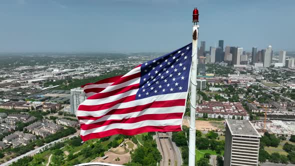 Houston Texas skyline. American flag proudly waves above cityscape. Aerial orbit. City in USA. alt