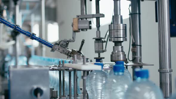 Water Factory Industrial Machine Puts Caps on Plastic PET Bottles with Water Close Up