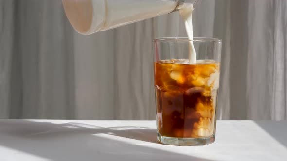 Milk Cream is Poured Into a Iced Coffee alt