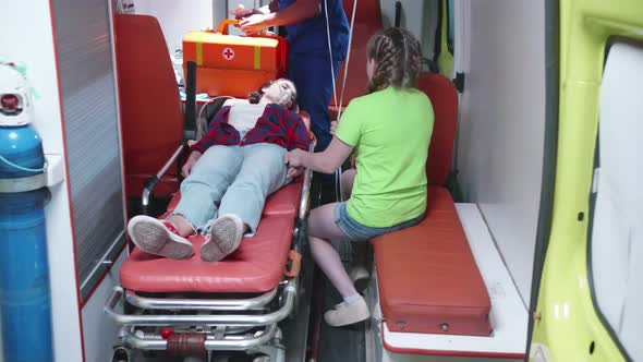 Injured Woman Lie on Strecher in Ambulcanse Car. alt