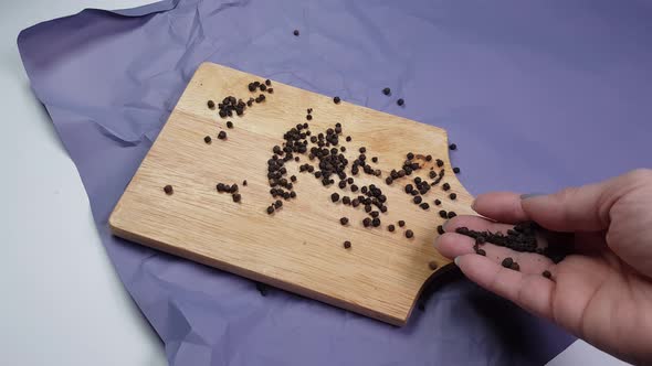 Peas of black pepper poured on a wooden cutting board