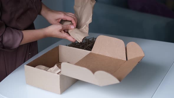 Woman is Packing Jars of Cosmetics in a Box to Send a Parcel Through a Delivery Service alt