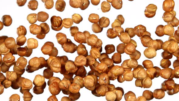 Super Slow Motion Shot of Flying Hazelnuts After Being Exploded on White Background at 1000 Fps. alt