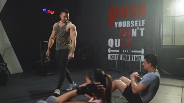 Asian Fitness trainer teach and motivate young beautiful sportsman and woman sit-up on floor. alt