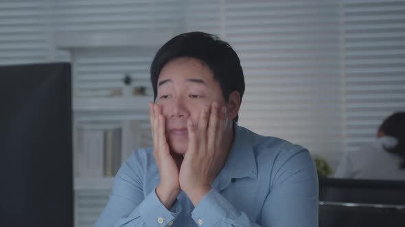 Tired Asian Male Worker Working on desktop computer in the Corporate Office, alt