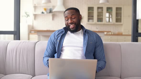 Happy African Man Using a Laptop for Video Call at Home alt