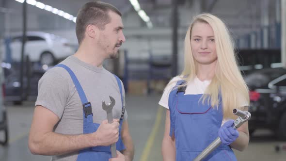 Young Professional Auto Mechanics Looking at Camera and Smiling, Talking To Each Other. Caucasian alt