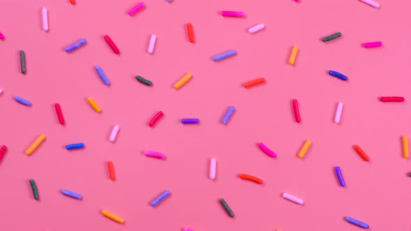 A Rotation Background of Sprinkles for Sweets on a Pink Background