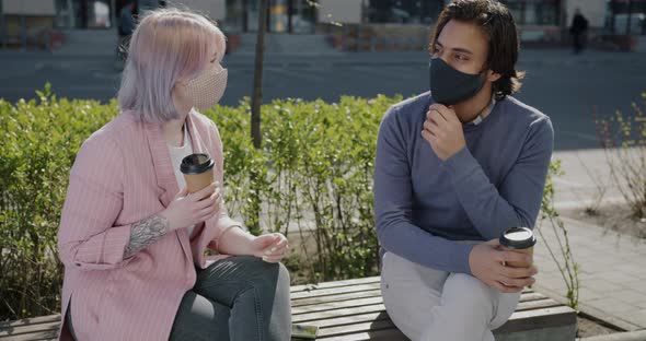Girl and Guy Wearing Face Masks Chatting Holding Take Out Coffee Outside in City Street alt