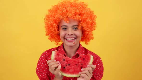 Laughing Teen Girl in Orange Hair Wig Biting Water Melon Slice Vitamin