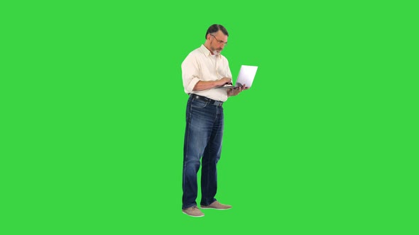 Upset Elderly Businessman Holding Laptop and Showing Disappointment on a Green Screen, Chroma Key. alt