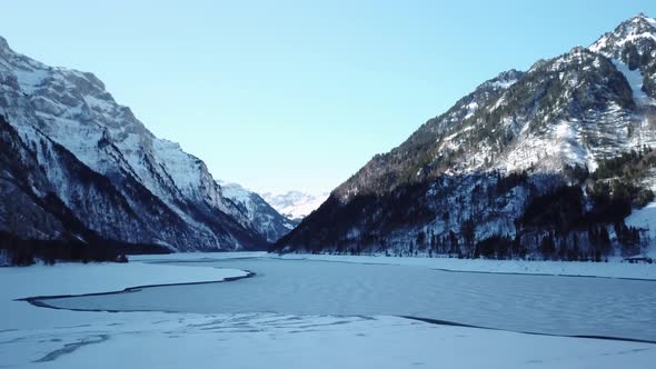 beautiful mountain range with a frozen lake in the middle, snowy forest and icy lake alt