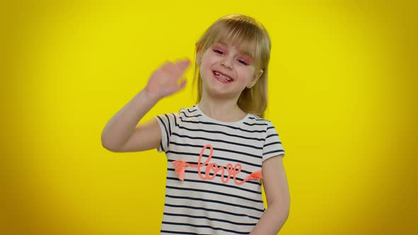Little Blonde Child Kid Girl Waves Hand Palm in Hello Gesture Welcomes Someone Positive Emotions alt