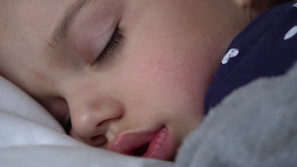 Authentic Cute Little Girl Sleeping Sweetly In Comfortable White and Grey Bed Close Up alt