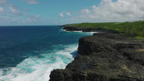 Aerial Top View of Waves Break on Rocks in a Blue Ocean alt