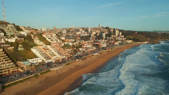 Aerial view flying across tourism resort Reñaca golden sand beach waterfront as ocean waves head tow alt