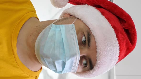 Man in Santa Hat Wearing Medical Mask Celebrate Christmas Alone at Home alt