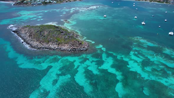 Aerial over shallow clear blue waters from Pinel Island to St. Martin (French Caribbean) on a bright alt