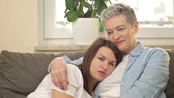 An Elderly Woman Gently Hugs Her Adult Daughter alt