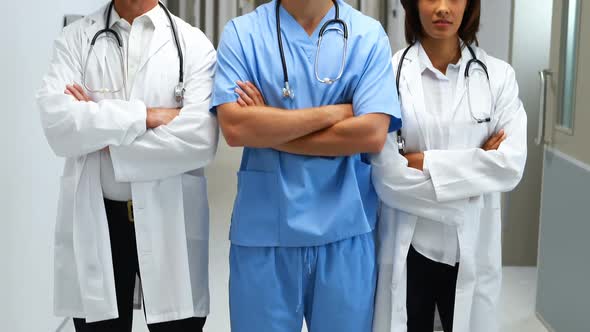 Portrait of doctors standing with arms crossed in corridor alt