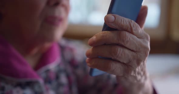 Close Up of handOld Grandmother with a Phone in Her Hands