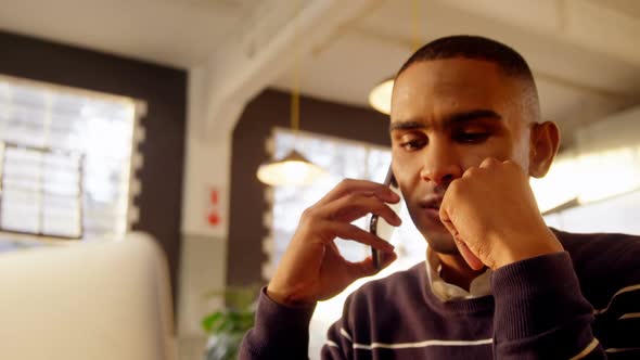 Man talking on mobile phone while using laptop 4k alt