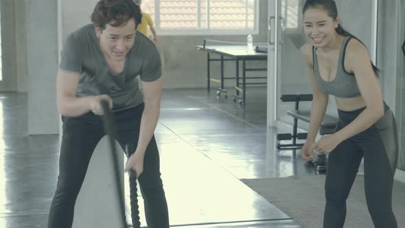 Young asian man strong doing battle rope exercise in the gym.