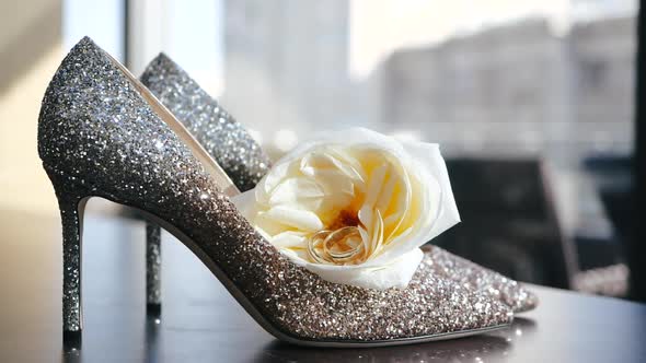 Pair of Gold Wedding Rings Lie in Middle of Yellow Flower on Women's Shoes of Bride, Decorated with alt