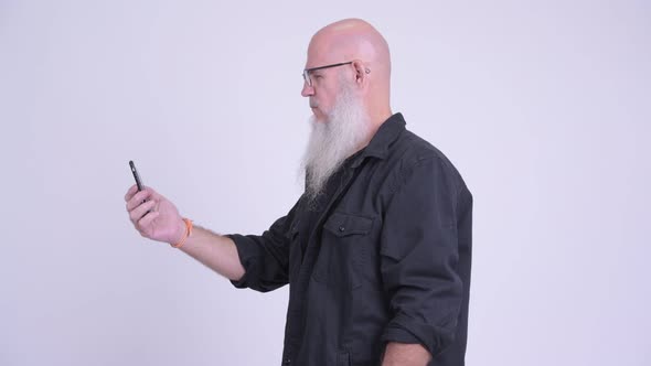 Profile View of Mature Bald Bearded Man with Phone Being Taken Away alt
