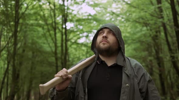Portrait of Positive Woodcutter Walking with Pro Ax in Wild Deciduous Forest. alt
