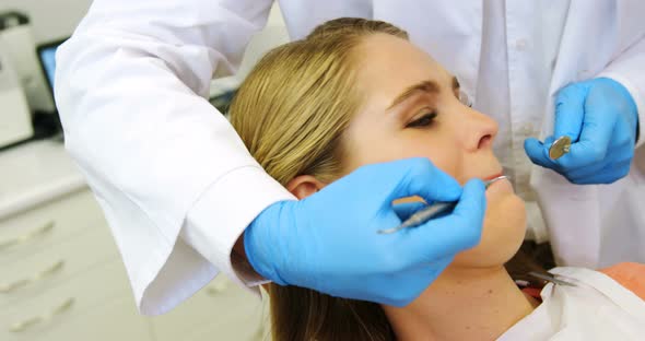Dentists examining a female patient with tools alt