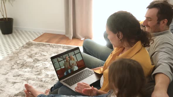 Family of Four Using Laptop for Video Connection with Grandparents or Family
