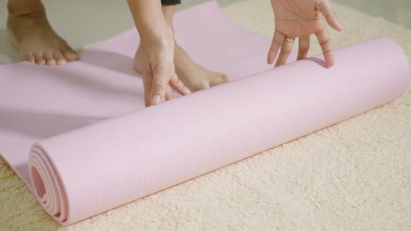 woman rolling fitness yoga pink mat before sports practice for exercise alt