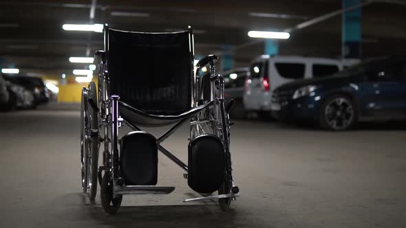 An Empty Wheelchair Stands in the Middle of a Car Park. Wheelchair Is Standing on the Road alt