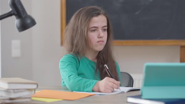Genius Little Person Raising Hand Answering in Video Chat on Tablet Sitting at Desk Indoors alt