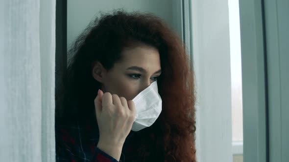 Pretty Lady Is Taking Off a Medical Mask While Sitting Next To the Window alt