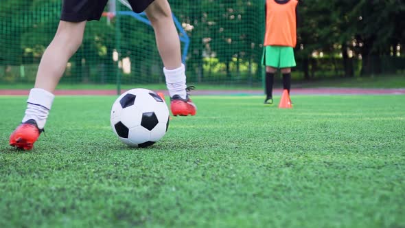 Boy's Feet in Football Shoes which Working Out the Kick with Ball During Training Day alt
