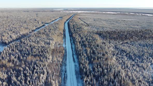 Aerial View From a Drone of a Road in the Middle of Snowcovered Trees and Snowcovered Forest on a