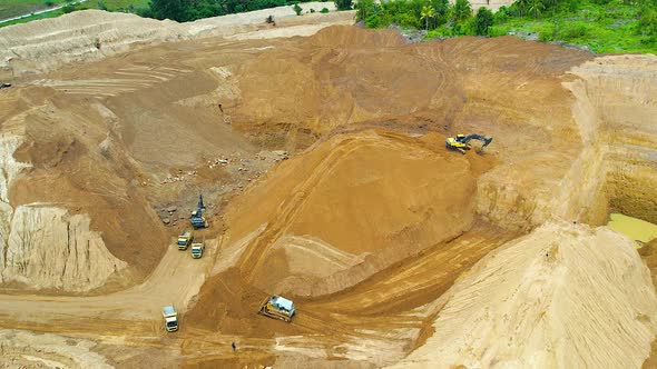 Aerial view of Work of trucks and the excavator in an open pit on gold mining. alt